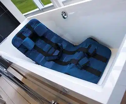 Siège de bain bleu réglable avec sangles noires, positionné dans une baignoire blanche. Aide à la toilette pour personnes à mobilité réduite.