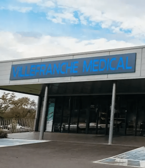 Façade moderne du bâtiment Villefranche Medical sous un ciel bleu. L'enseigne bleue affiche "VILLEFRANCHE MEDICAL".